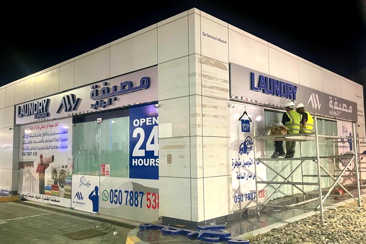 Shopfront signboard for Al Waqaed Laundry at an ADNOC station, Abu Dhabi