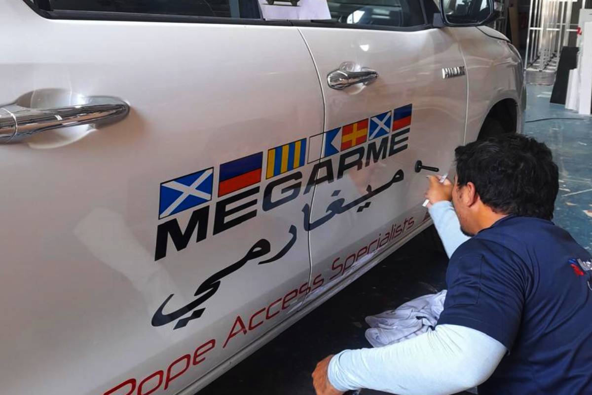 Megarme fleet lettering and maritime flag graphics on a pickup truck in Abu Dhabi.